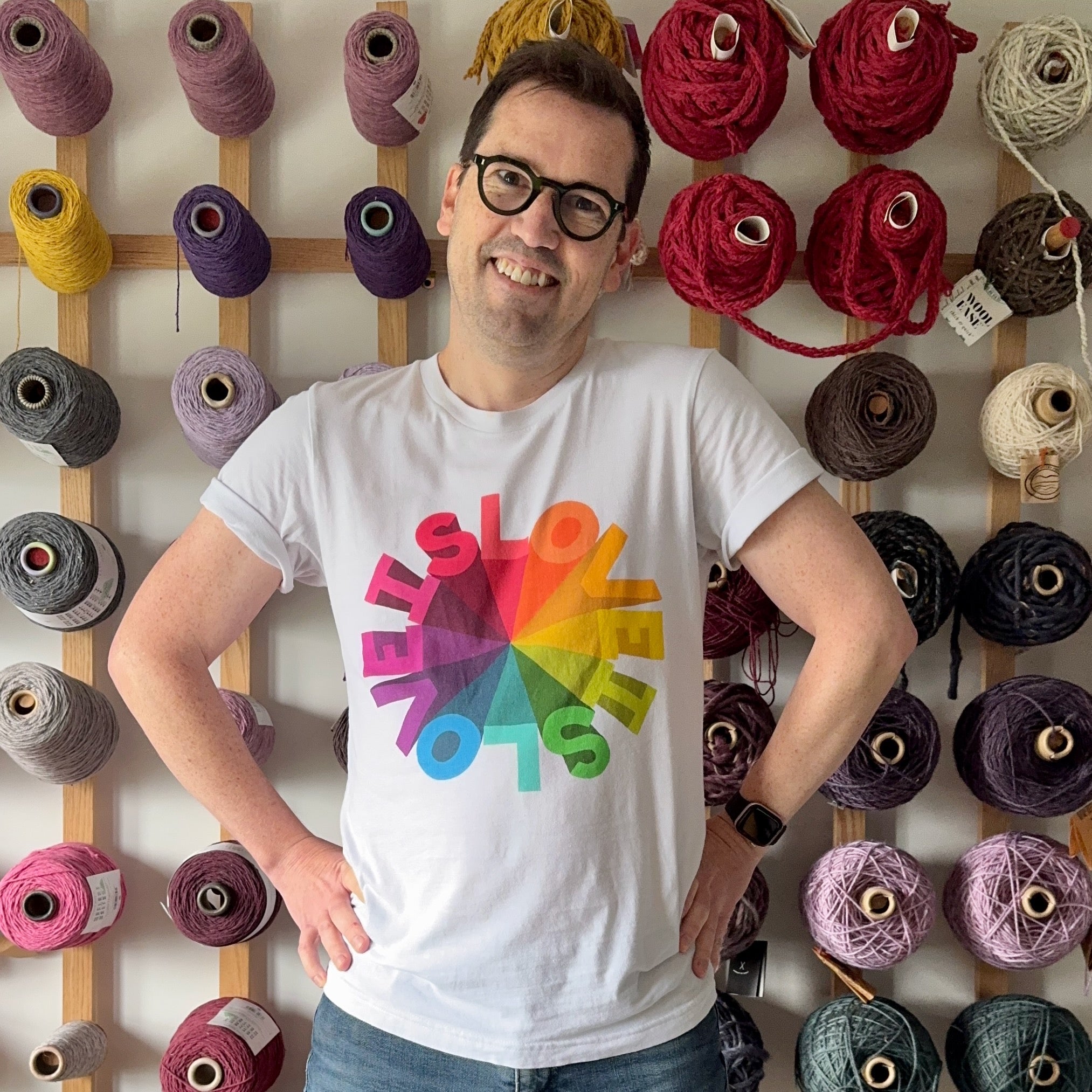 A portrait of Jedd wearing a white t-shirt with a rainbow design that reads Love is Love is Love in a circle