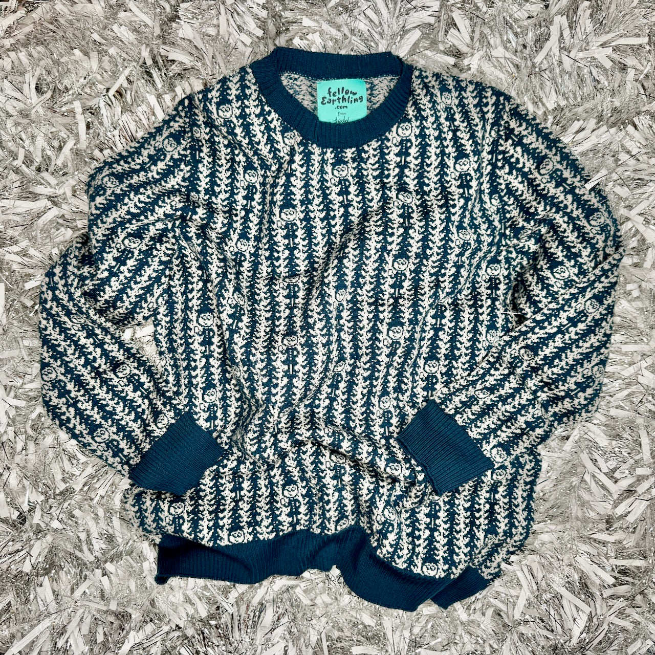 A knit sweater with a tree design and a small character repeating in the pattern.