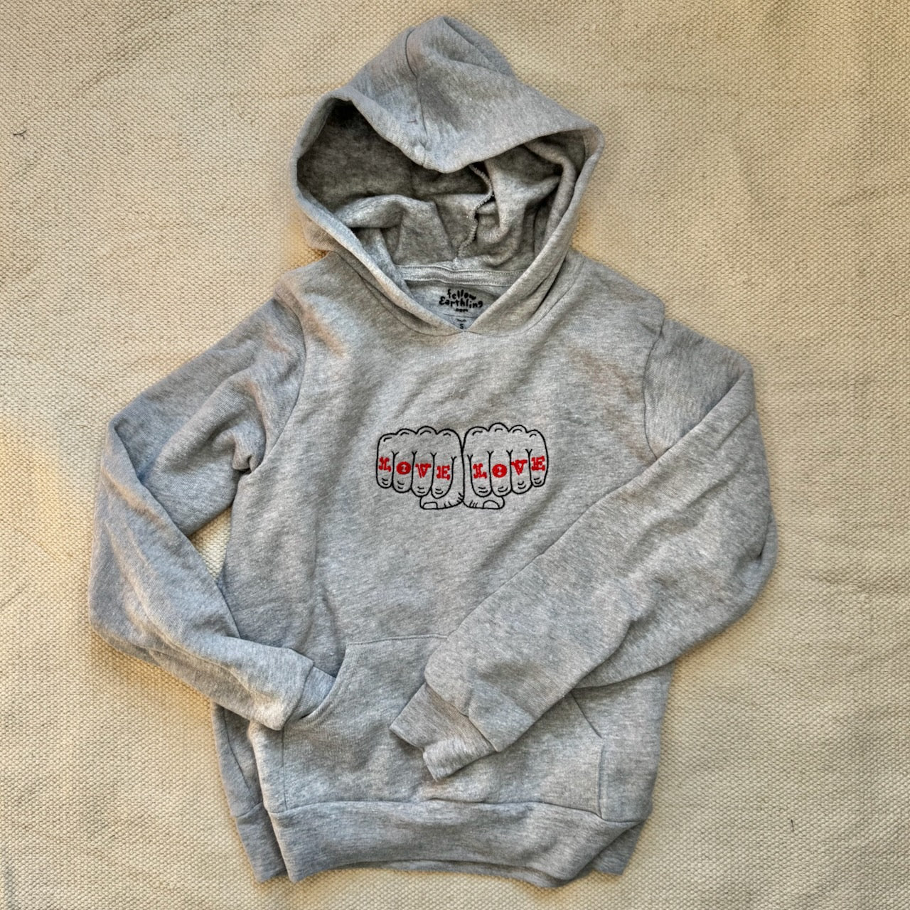 A youth size gray hoodie with a design that reads Love Love