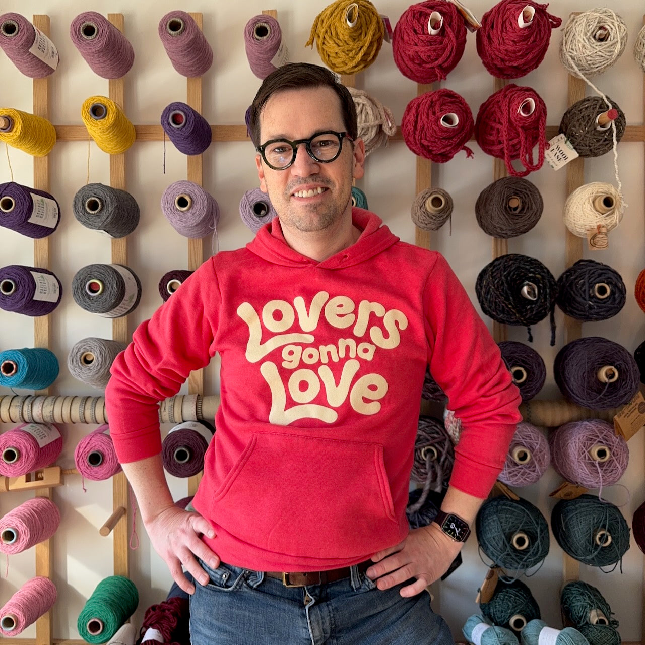 A portrait of founder Jedd Flanscha wearing a red hoodie reading "Lovers Gonna Love"