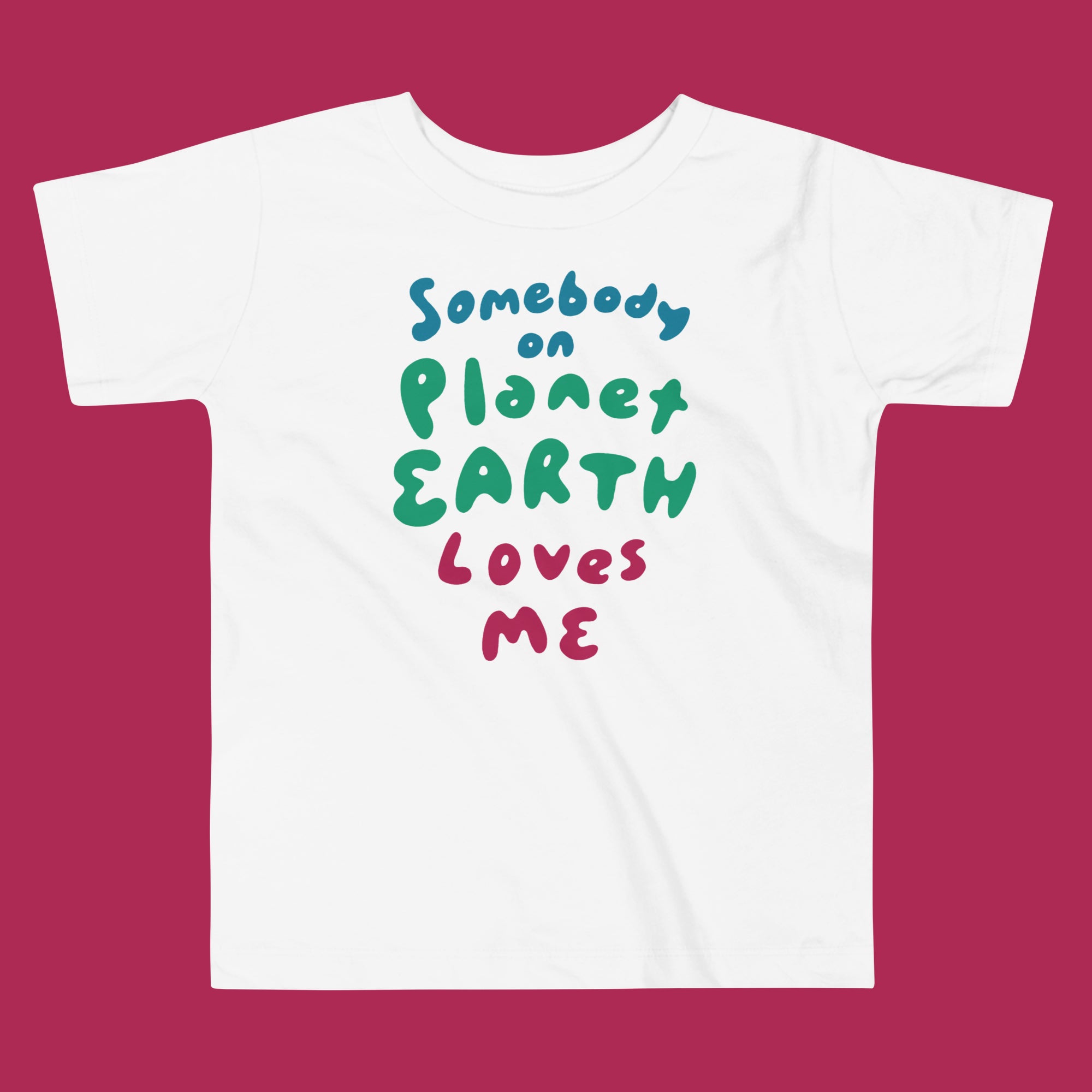 White t-shirt with colorful text 'Somebody on Planet Earth Loves Me' on a magenta background
