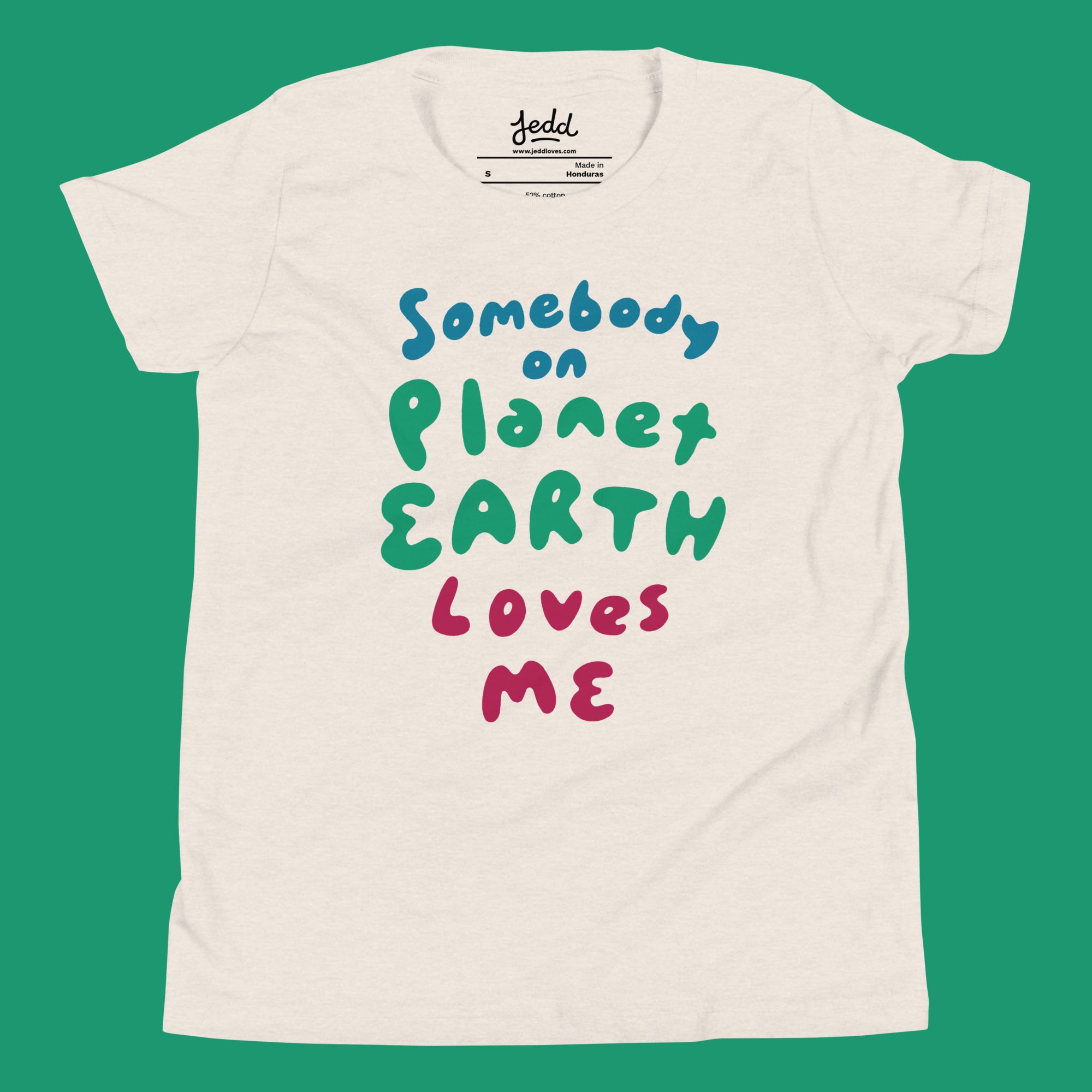 A cream colored t-shirt with text that says Somebody on Planet Earth Loves Me