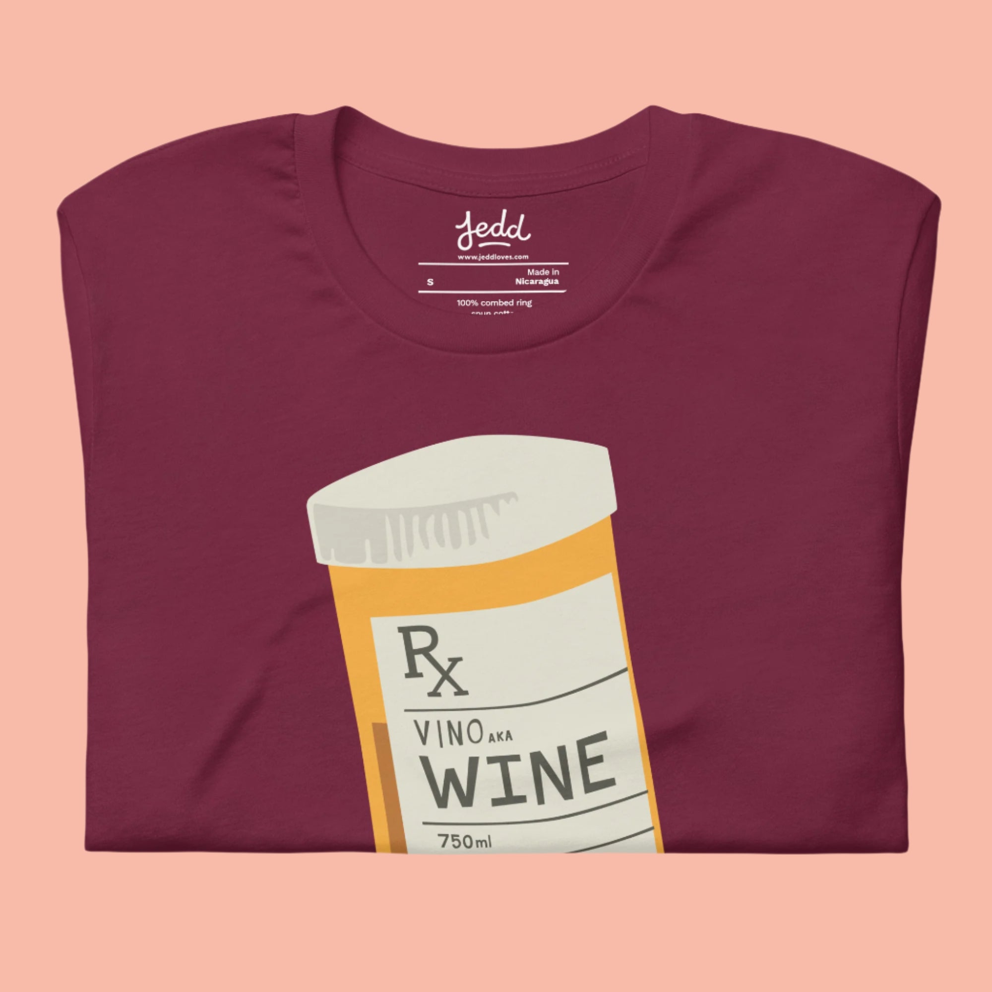A folded maroon shirt with a prescription bottle illustration that reads "wine"