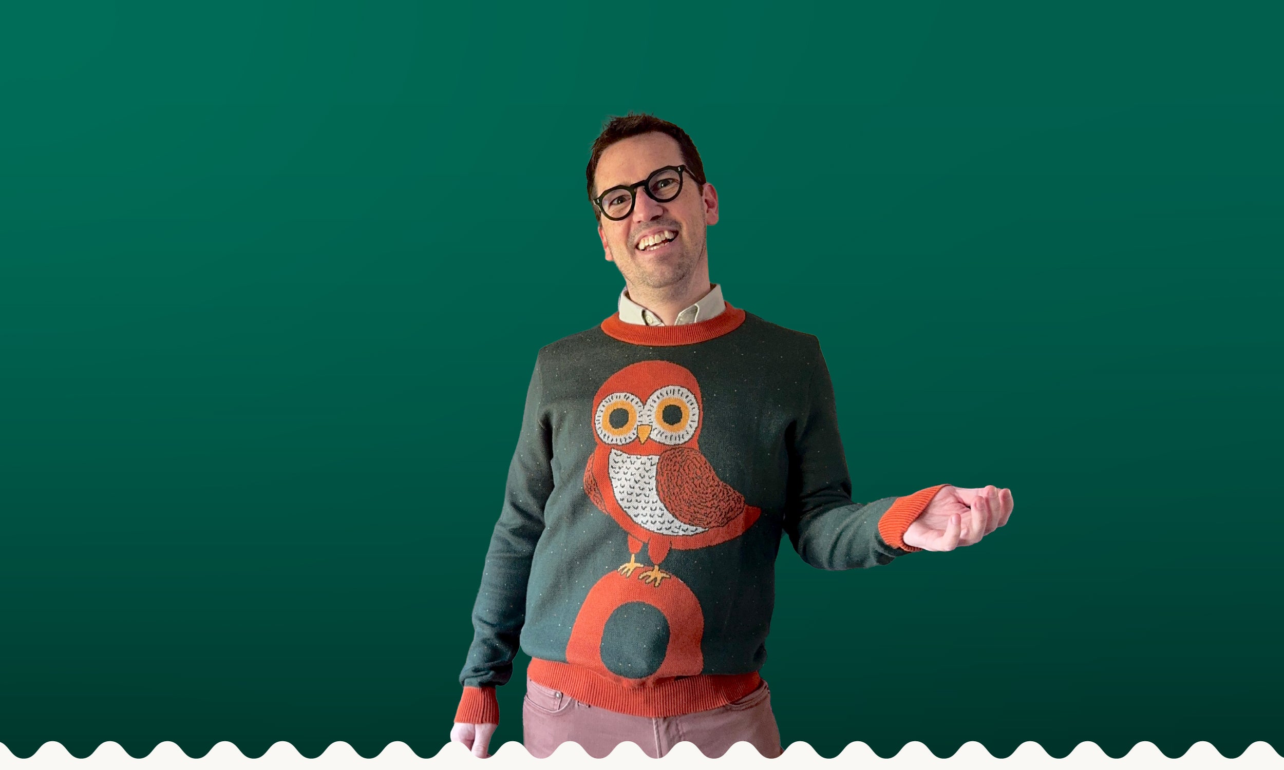 A portrait of Jedd wearing a green sweater with an orange owl design.