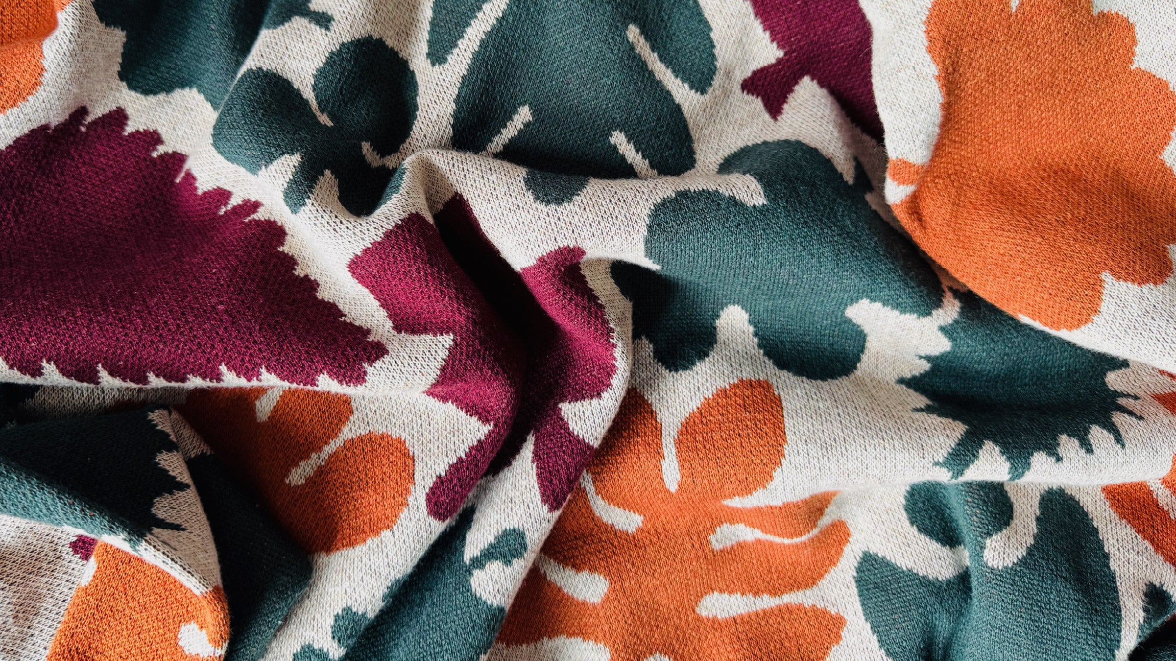 Close-up of colorful floral fabric with orange, green, and purple patterns.