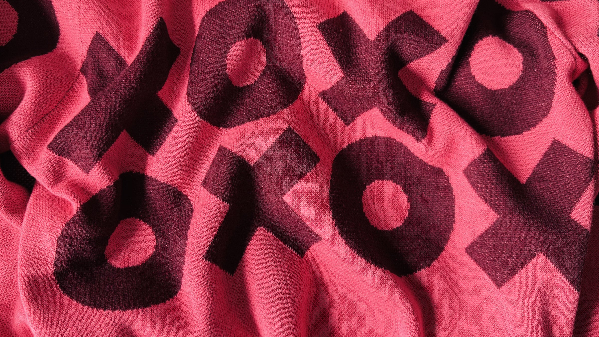 Zoomed in knit detail of a pink sweater with an XOXO design.