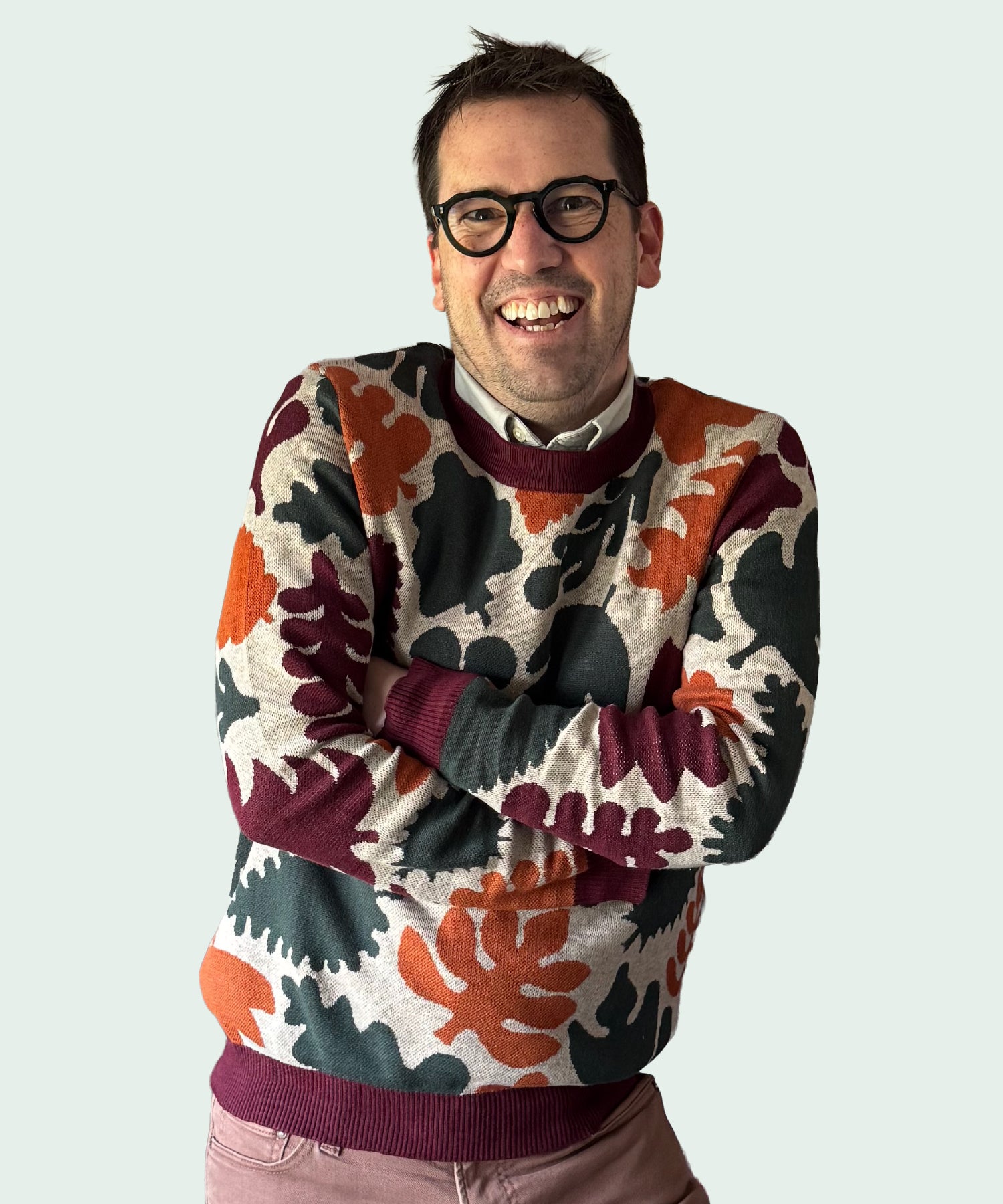 Man wearing a colorful patterned sweater on a plain background