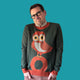 Man wearing a sweater with an owl design on a teal background