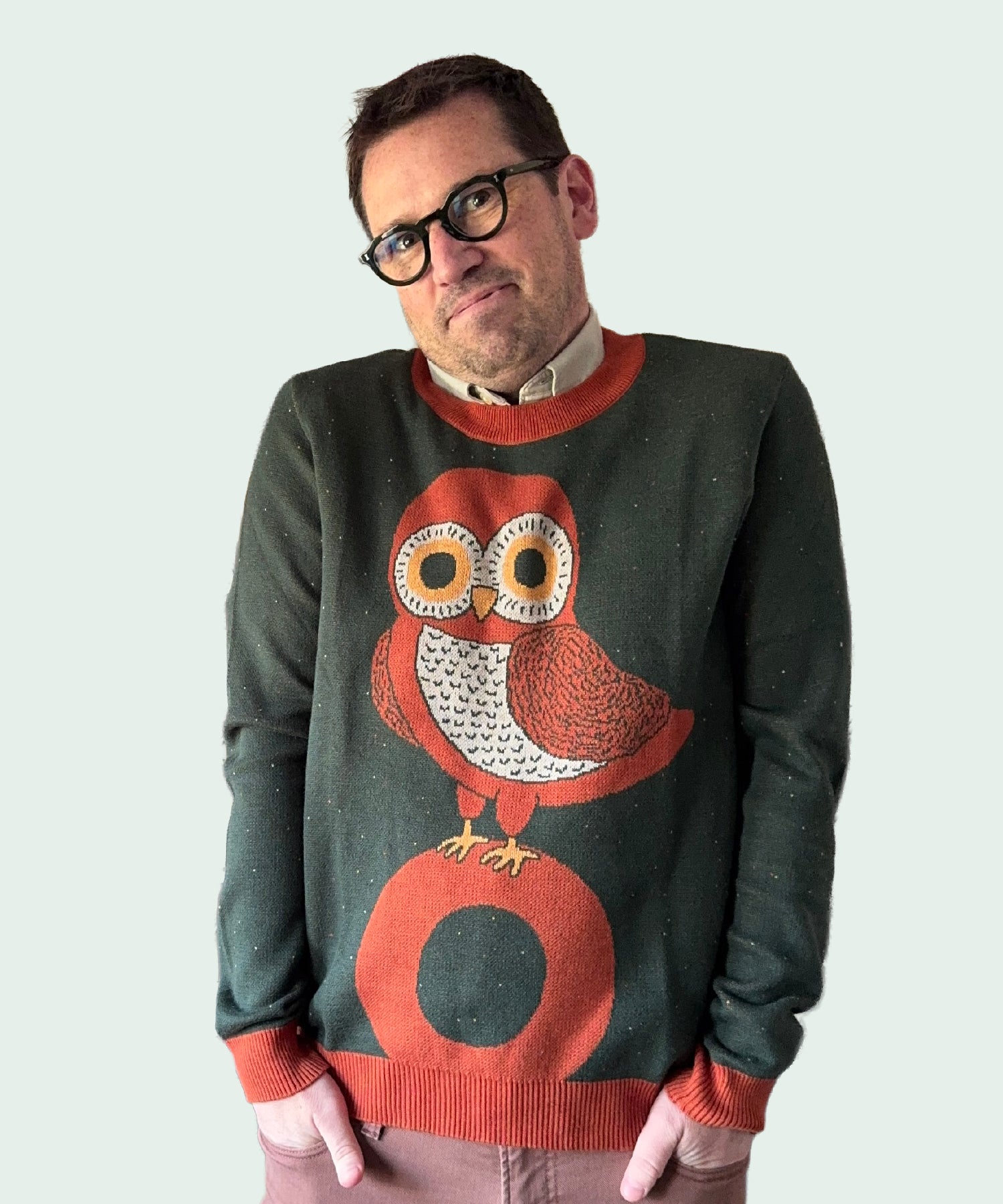 Man wearing a sweater with an owl design on a plain background
