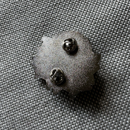 Detail of the back of an enamel pin with two pins and butterfly closures.