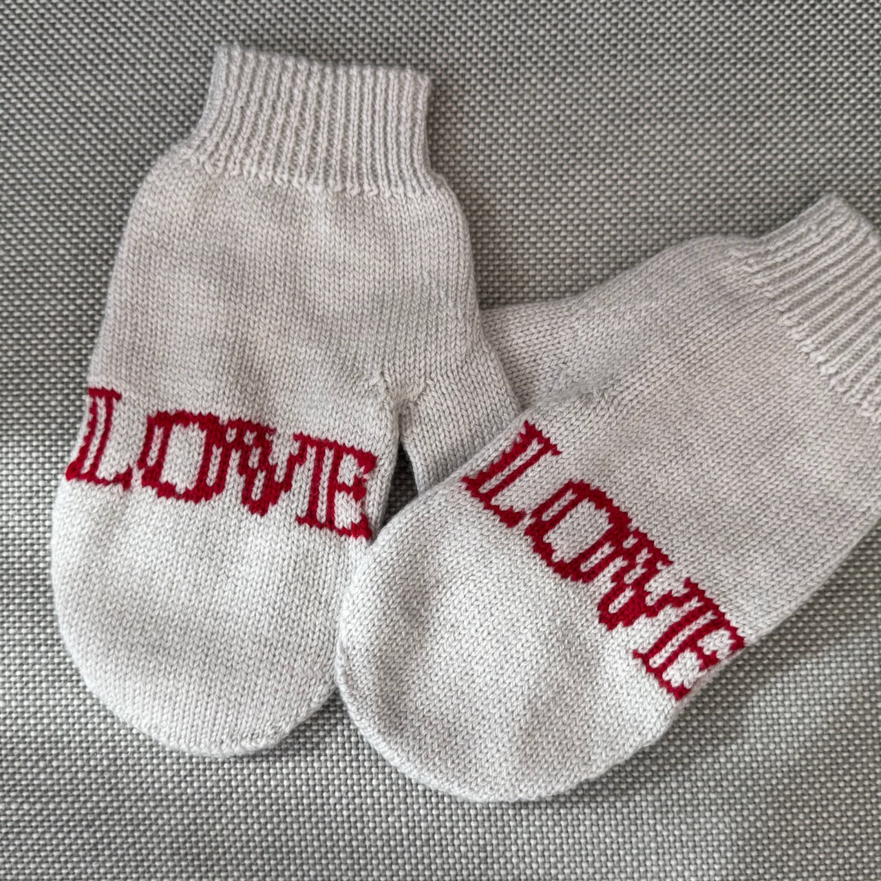 A pair of mittens that has the word Love on each hand