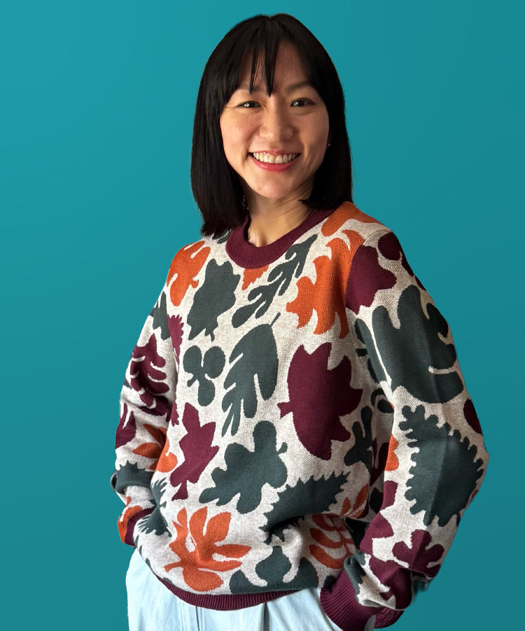 Person wearing a patterned sweater against a teal background