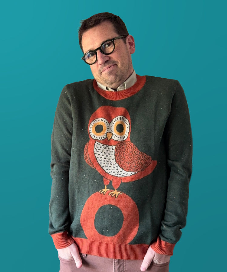 Man wearing a sweater with an owl design against a teal background