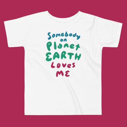 White t-shirt with colorful text 'Somebody on Planet Earth Loves Me' on a magenta background